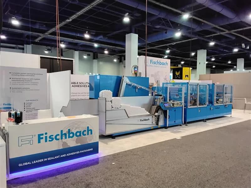Wide aisle view of a white-and-blue exhibit with integrated processing equipment.