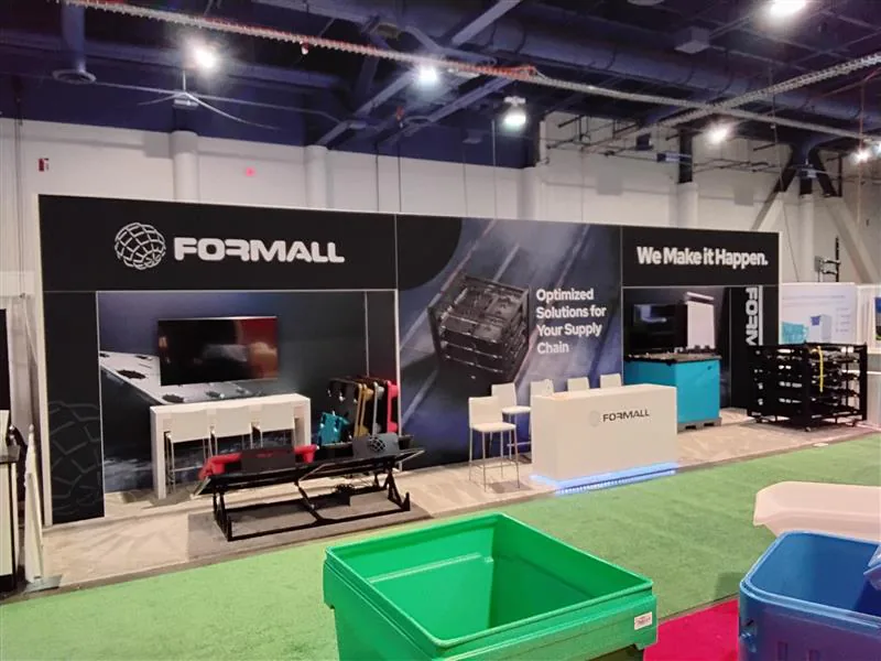 Open exhibit with a dark graphic wall, demonstration machinery, and bright floor accents.