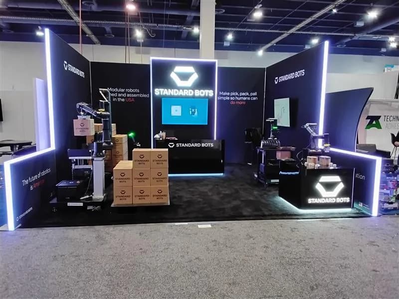 Dark technology exhibit framed by illuminated vertical structures and demonstration stations.